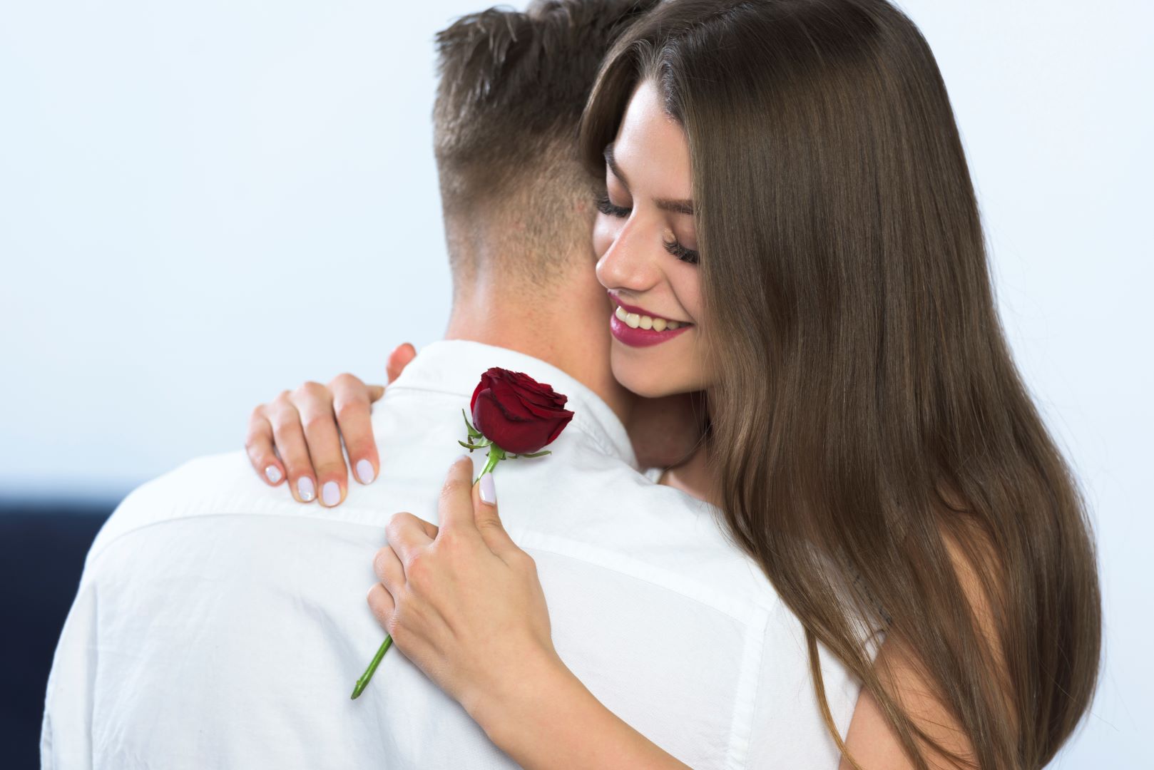 زوج أهدى لزوجته زهرة حمراء وهي تحتضنه بمحبة