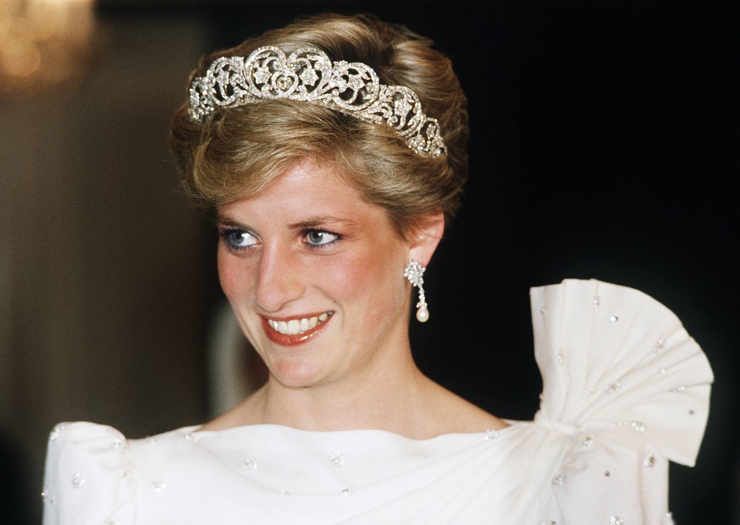 الأميرة ديانا، أميرة ويلز، Diana, Princess of Wales ترتدي فستانًا أبيض من تصميم ديفيد وإليزابيث إيمانويل، وتضع تاج سبنسر، خلال حضورها مأدبة رسمية في 16 نوفمبر 1986 في البحرين. مصدر الصورة: Anwar Hussein/WireImage)