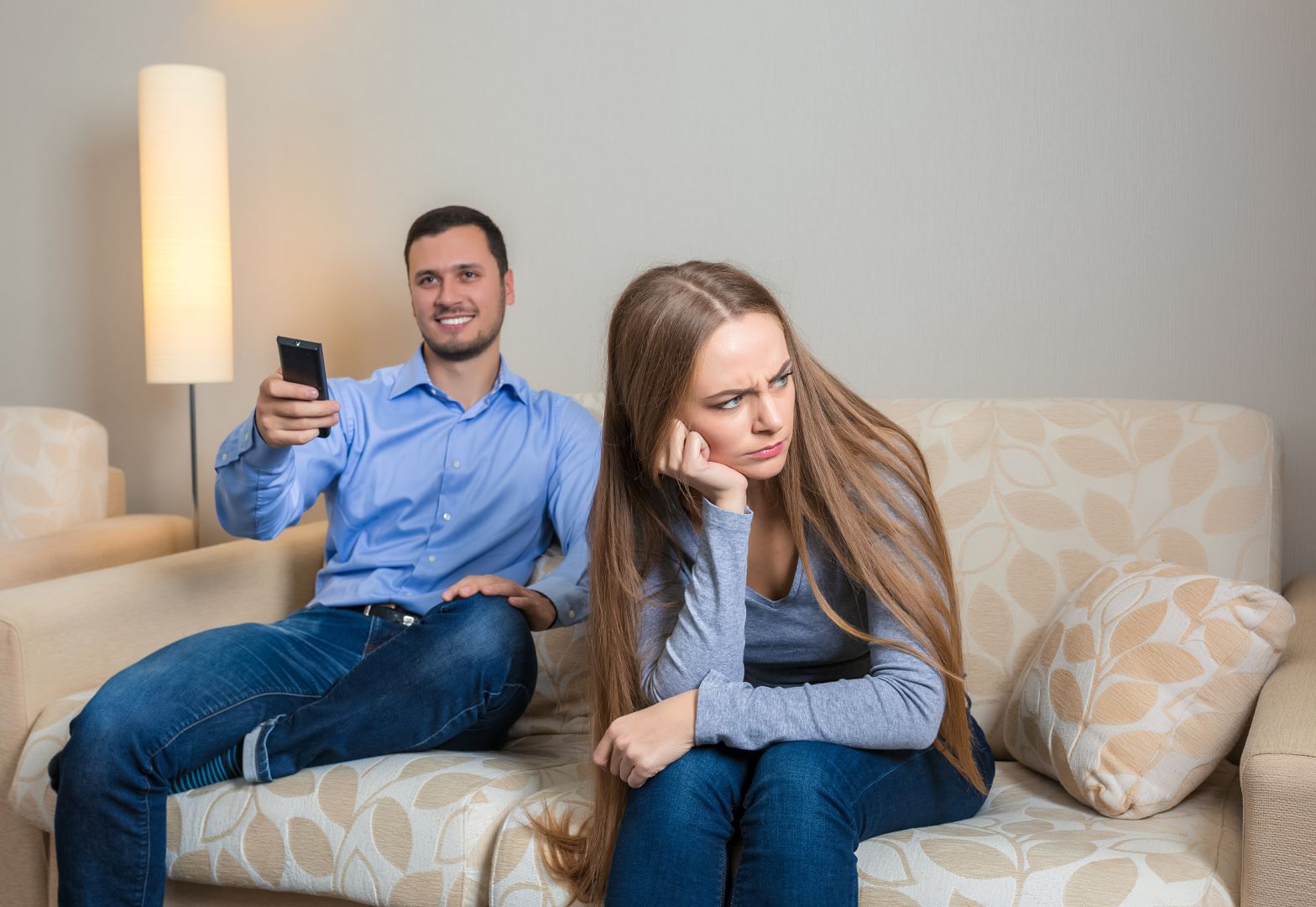زوج يستمتع بوقته في مشاهدة التلفزيون والزوجة تبدو متضايقة من انشغال زوجها   