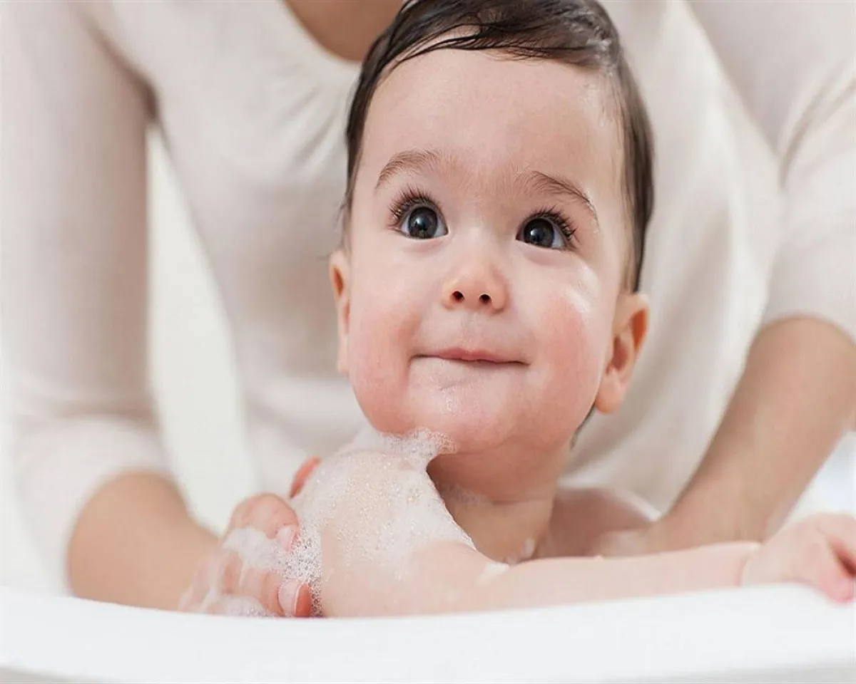 صورة لأم تقوم بتحميم الطفل الرضيع