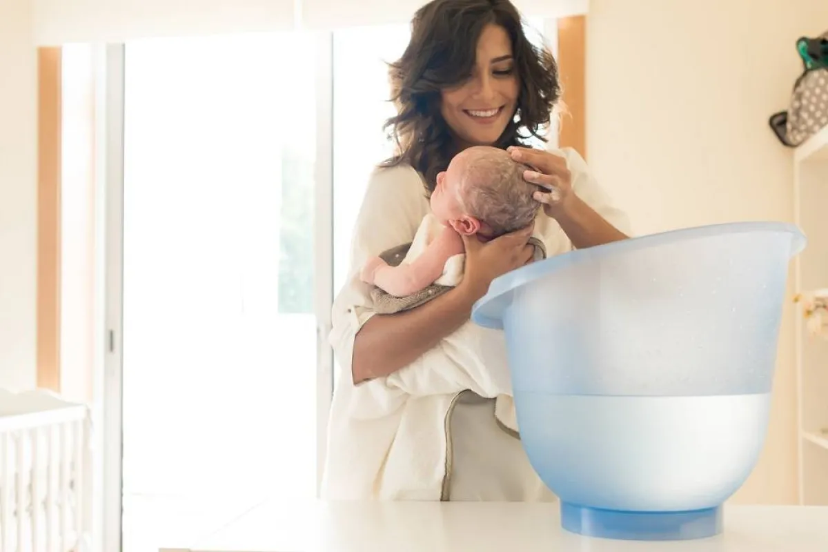 صورة لأم تقوم بغسل رأس طفلها