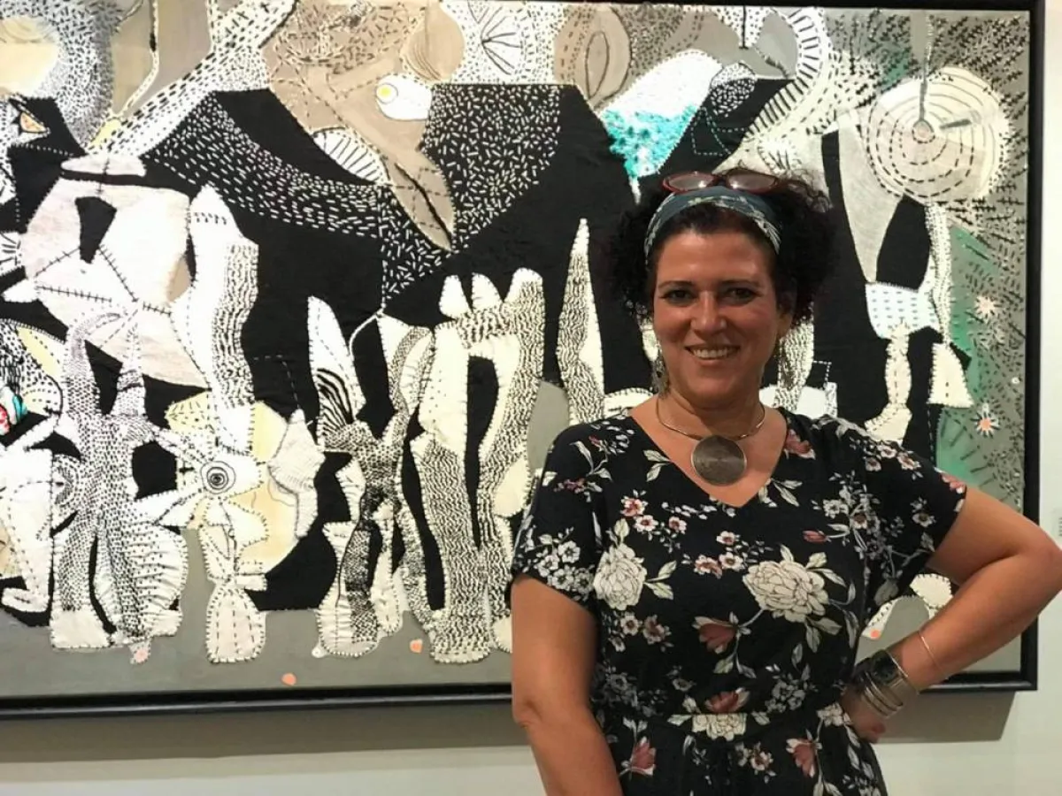 فنانة تقف أمام إحدى لوحاتها