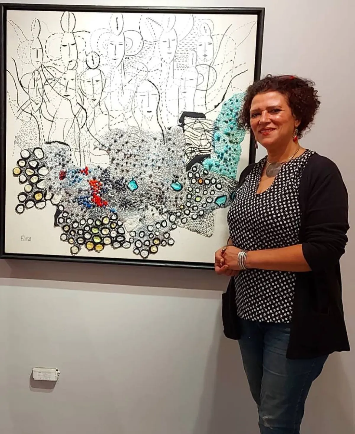 فنانة تقف أمام إحدى لوحاتها