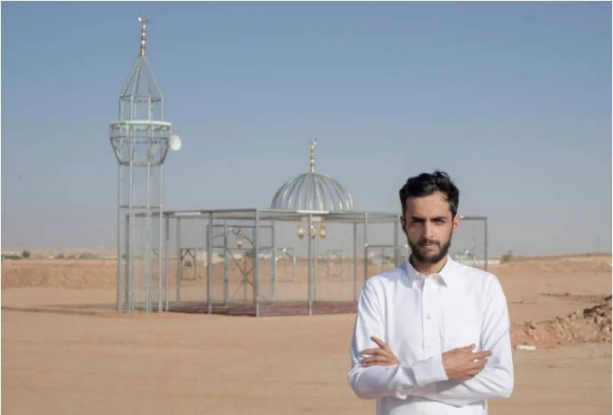 الفنان عجلان غارم مع أحد أعماله الفنية 