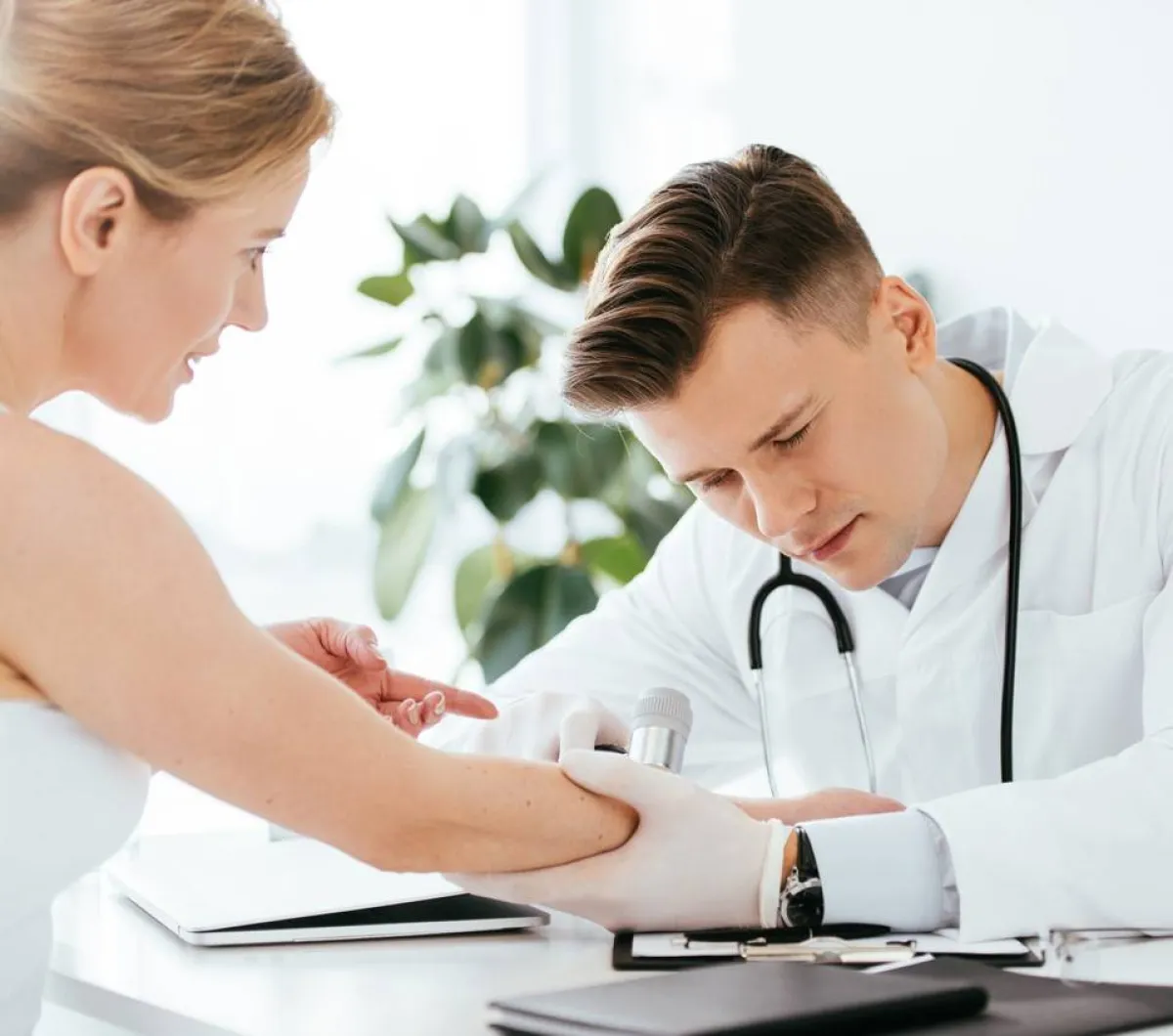 طبيب جلدية يفحص العلامات في يد المريضة