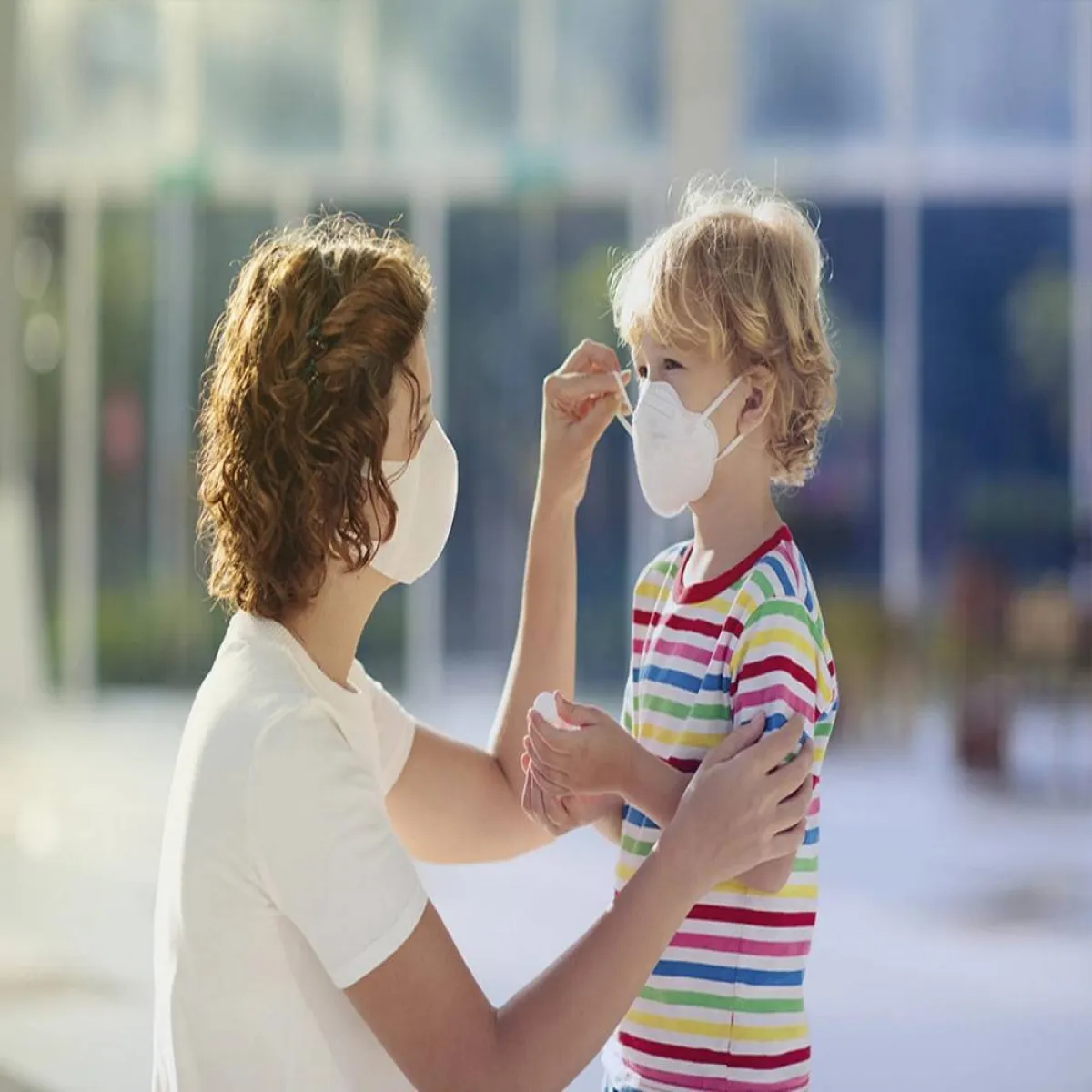 صورة لأم تقوم بتعليم الطفل ارتداء الكمامة 