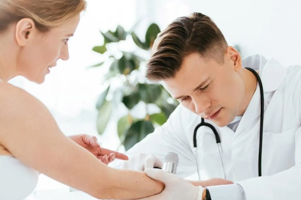 طبيب جلدية يفحص العلامات في يد المريضة