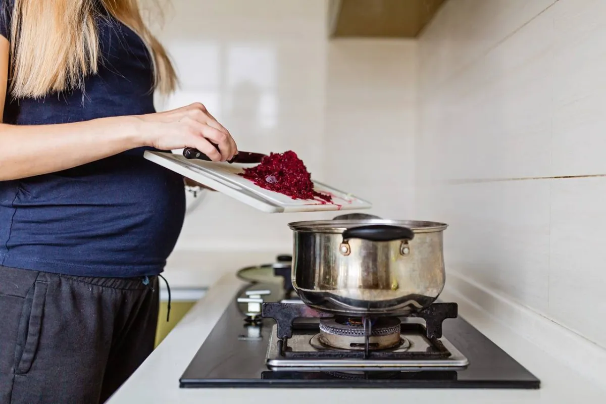 صورة لحامل تقوم بالطبخ