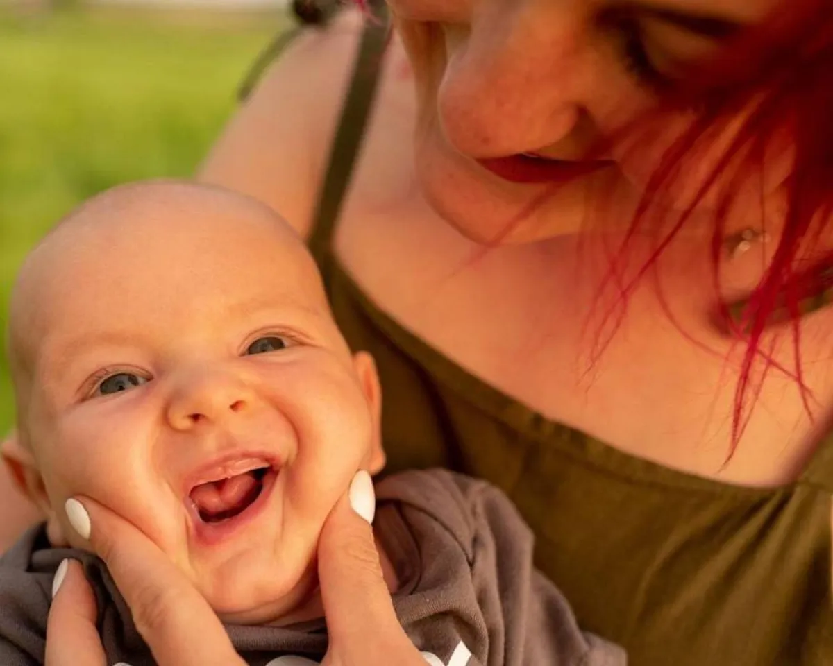 صورة لأم تحاول فتح فم طفلها لتنظيفه