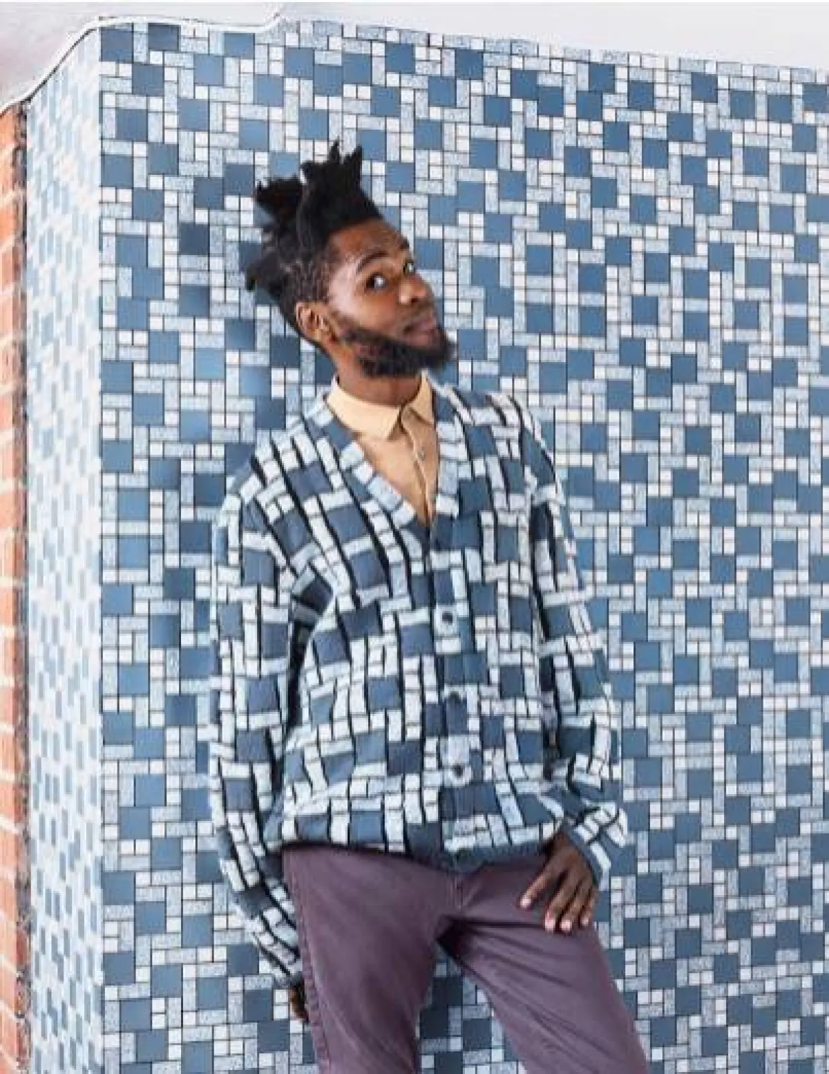 شاب يقف أمام حائط  يرتدي ملابس تتماهى مع الخلفية