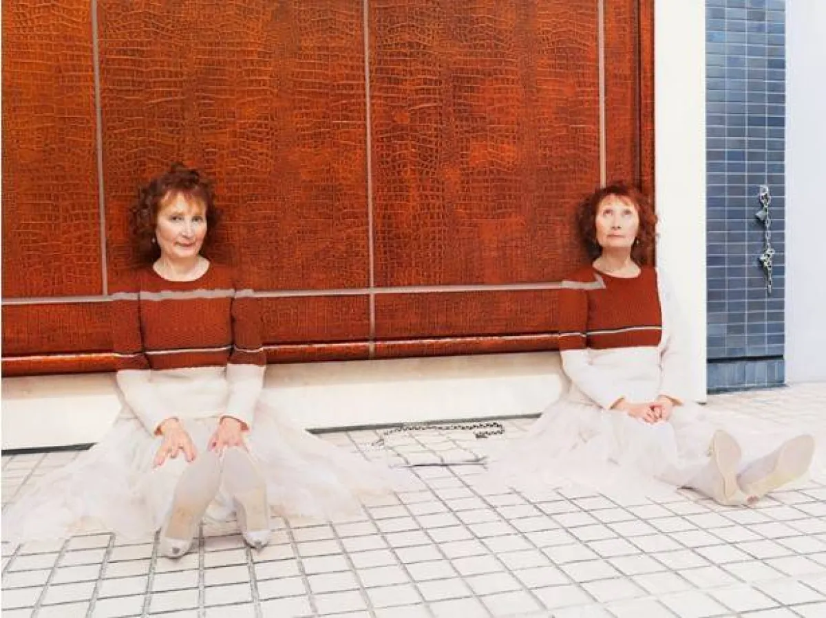 فتاتان تجلسات ترتديان ملابس سترة تتماهى مع الخلفية