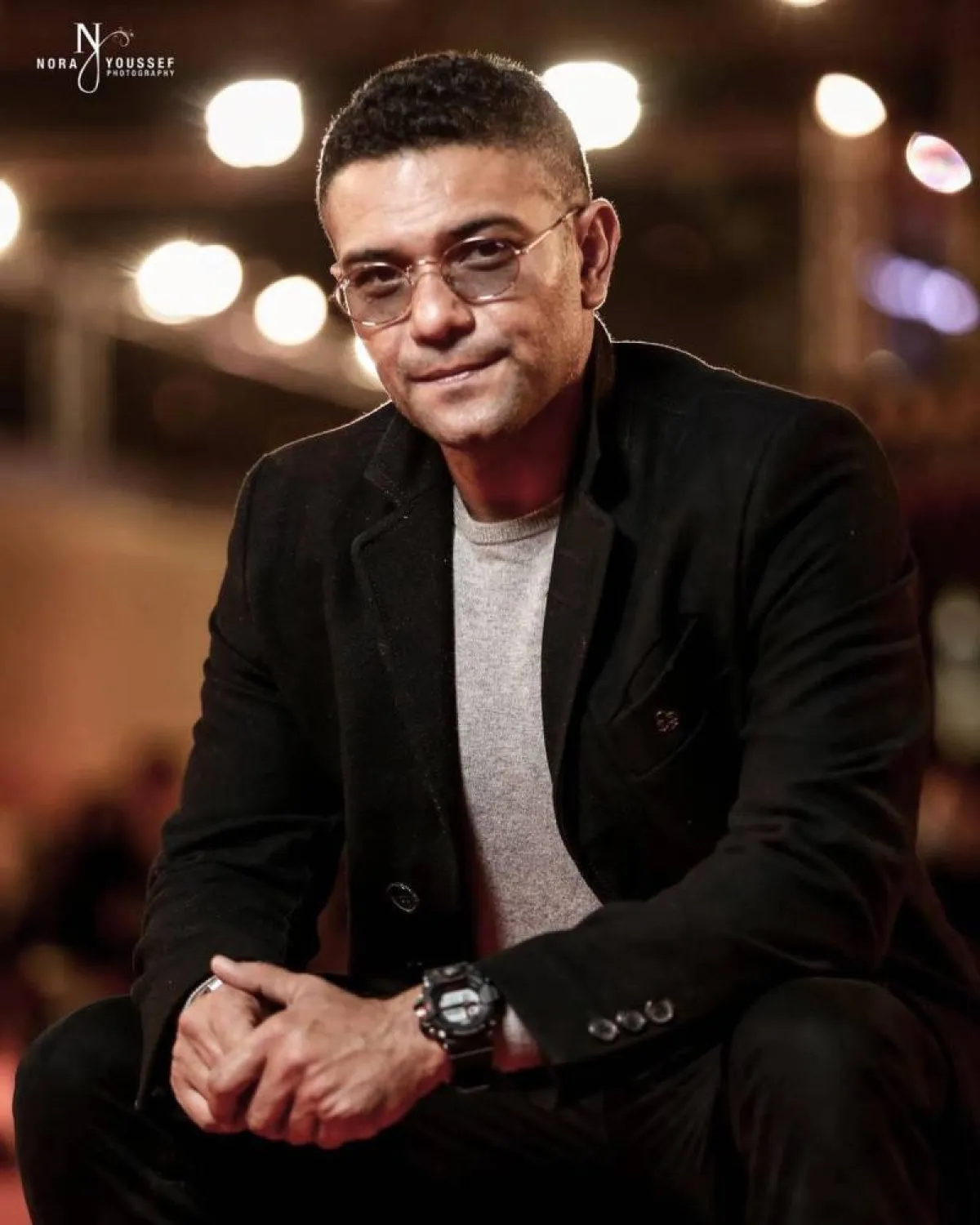 آسر ياسين ببليزر أسود وتيشرت رمادي وبنطلون اسود 