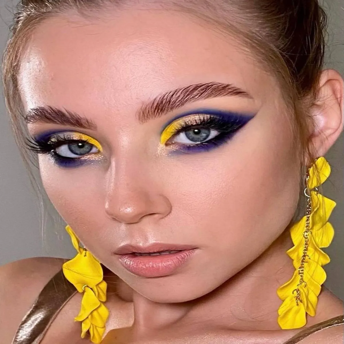 مكياج عيون غرافيكي بظلال العيون الأصفر والأزرق الداكن والبنفسجي والأسود