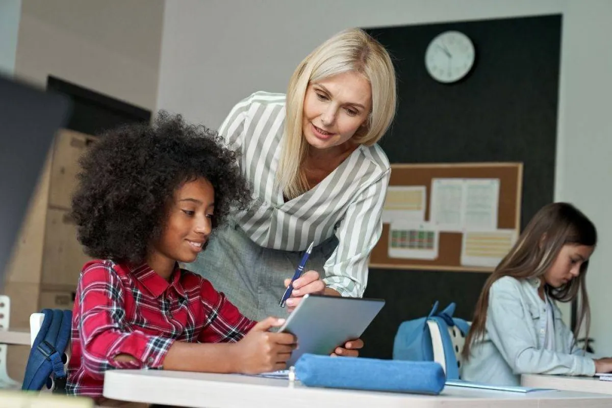 صورة تظهر معلمة تعلم طالبتان