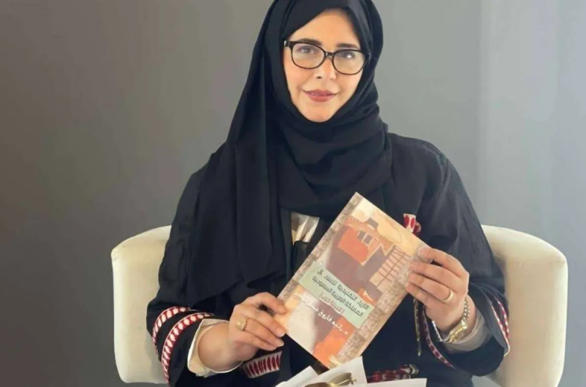 الدكتورة رانية خوقير مع كتابها عن الأزياء التراثية لنساء قبيلة حرب 