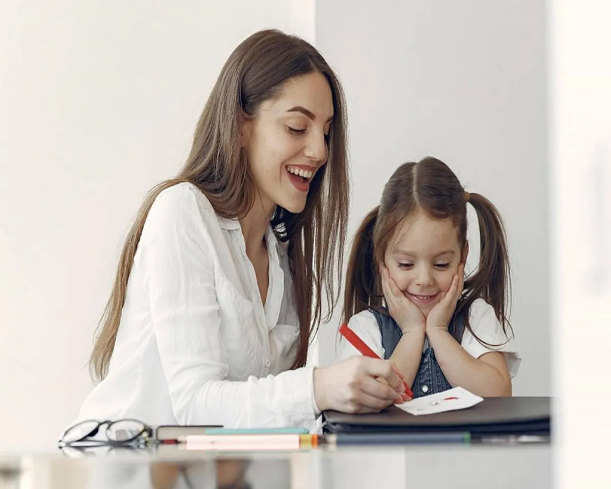 صورة لأم تحاول تعليم طفلتها الكتابة 