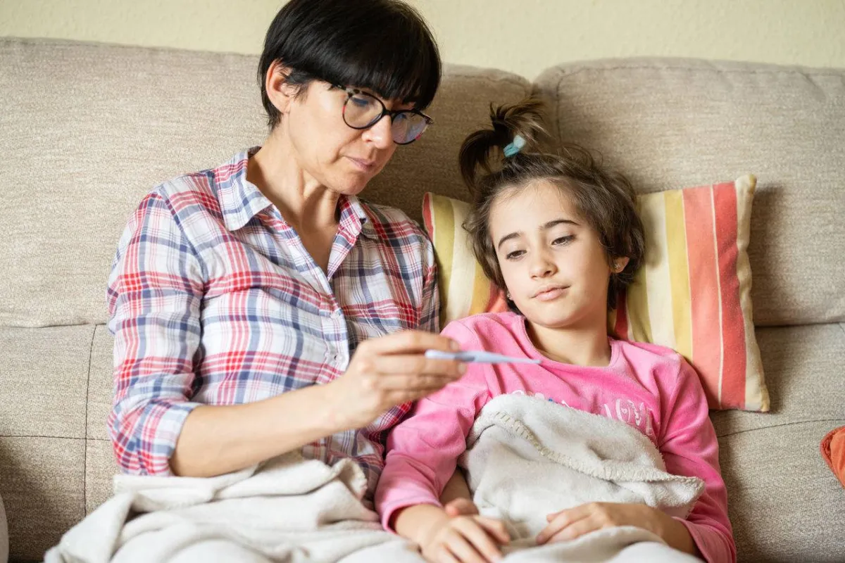 صورة لأم تقيس درجة حرارة طفلتها