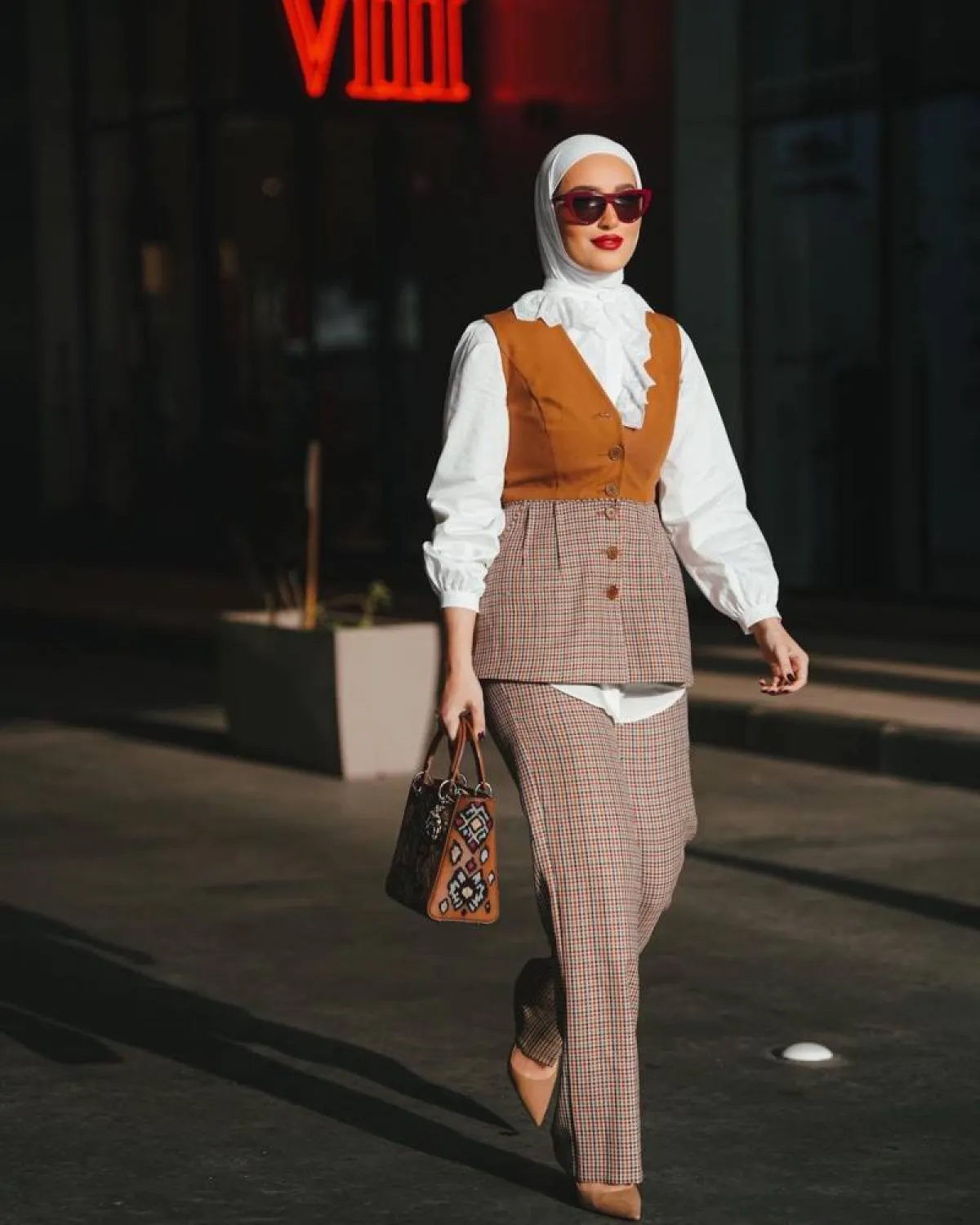 دلال الدوب ببدلة كاروهات ببليزر بدون أكمام مع بلوزة بيضاء واسعة 