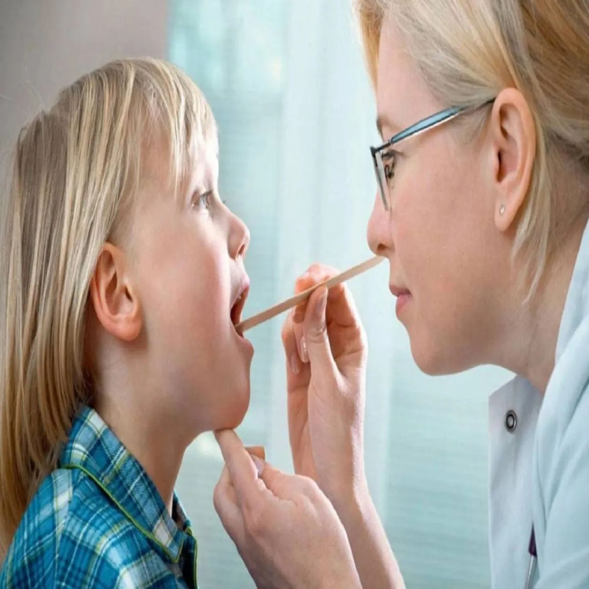 صورة لطبيب يفحص حلق الطفل 