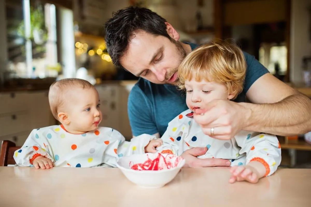 صورة لأب يقدم الطعام  الصحي لأطفاله لأن الدراسات أثبتت أن الأطفال يقبلون على الطعام من الأب أكثر من الأم