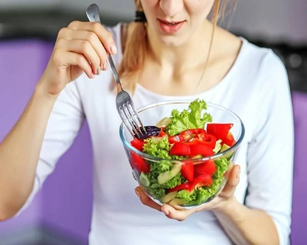 صورة لمأة تتناول طبق من السلطة الخضراء