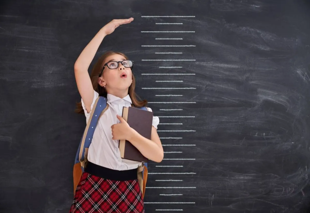 صورة لطفلة تحاول أن تقيس طولها لأنها تقارن نفسها بأطفال آخرين