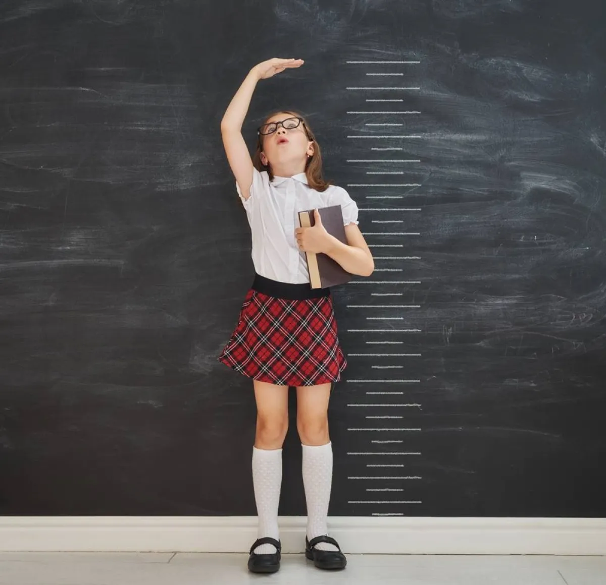 صورة لطفلة تحاول ان تعرف مقدار نموها من ناحية الطول وتفرح بذلك