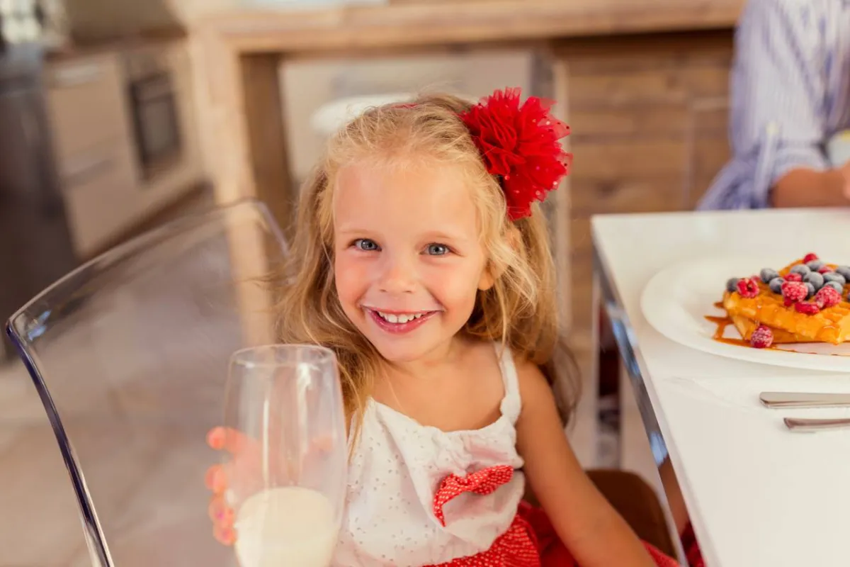 صورة لطفلة تشرب كوب كبير من اللبن