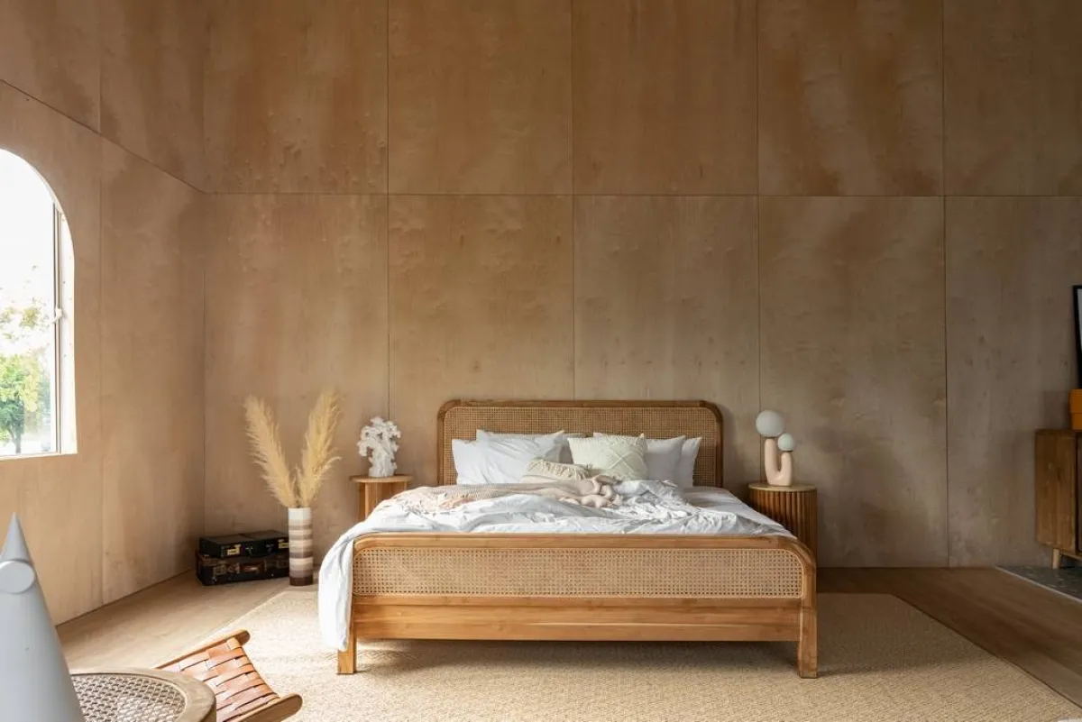 غرفة ذات جدران مصنوعة من الخشب الرقائقي، وتتألّف من سرير ذي رأسيّة مصنوعة من الروطان