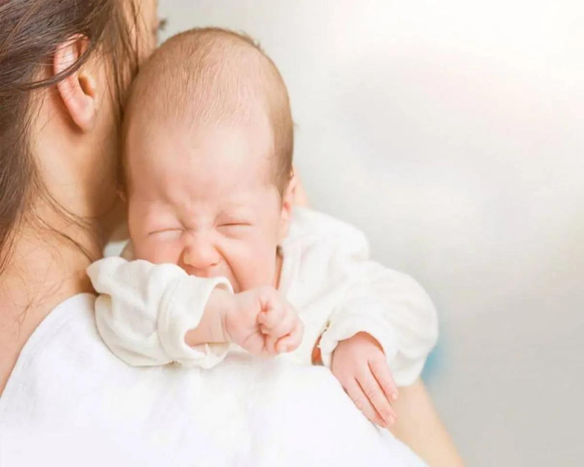 صورة لأم تقوم بحاول مساعدة الرضيع على التجشوء