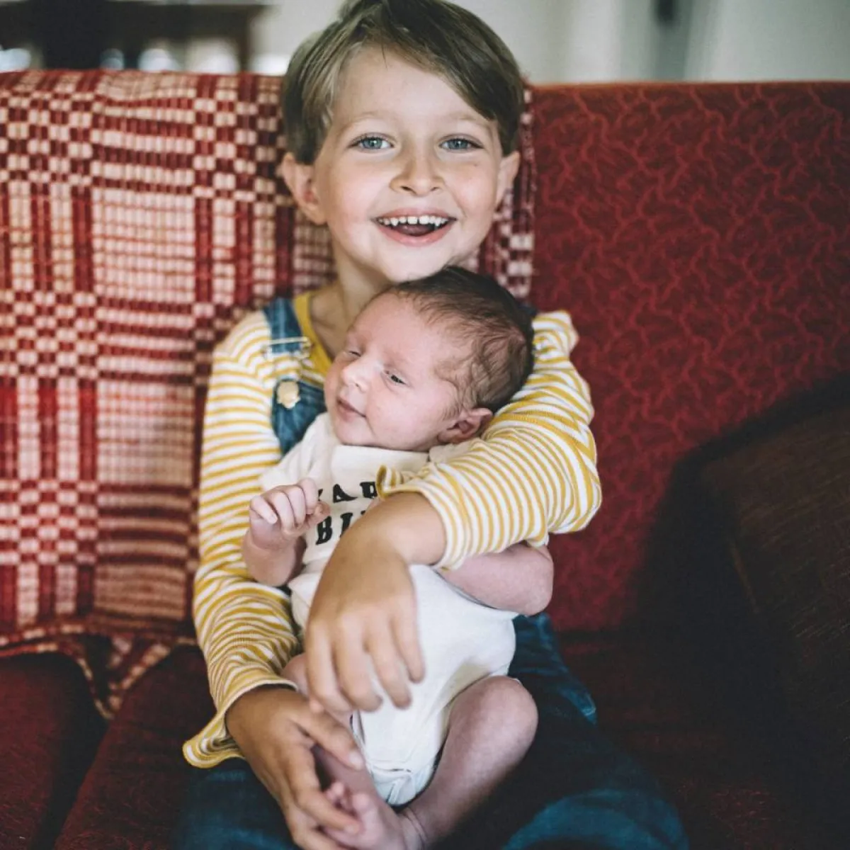 صورة لطفل يحمل أخيه المولود