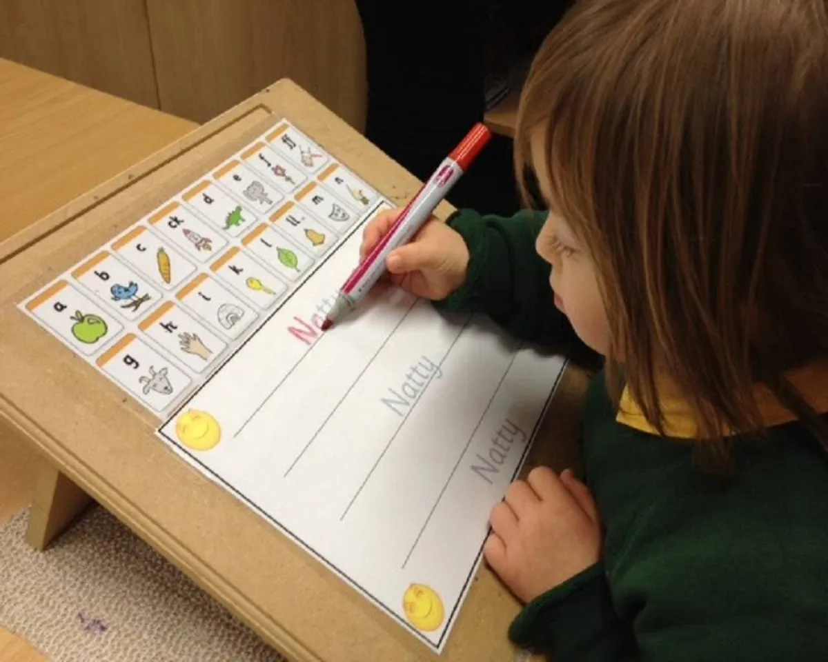 صورة لطفلة صغيرة تحاول كتابة الحروف