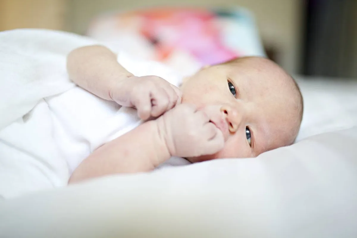 صورة لمولود يضع يده في فمه