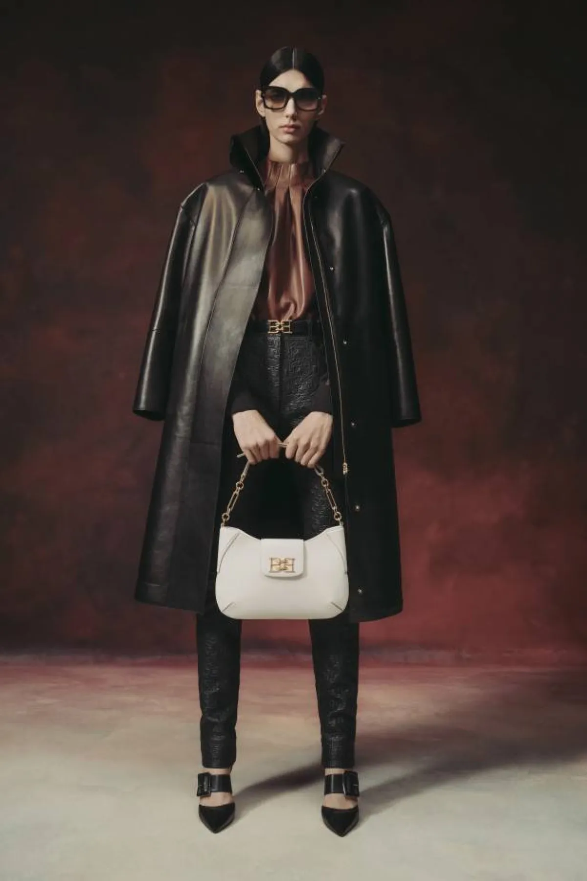 بنطلون جلد أسود ضيق مع معطف أسود طويل وبلوزة ساتان بني