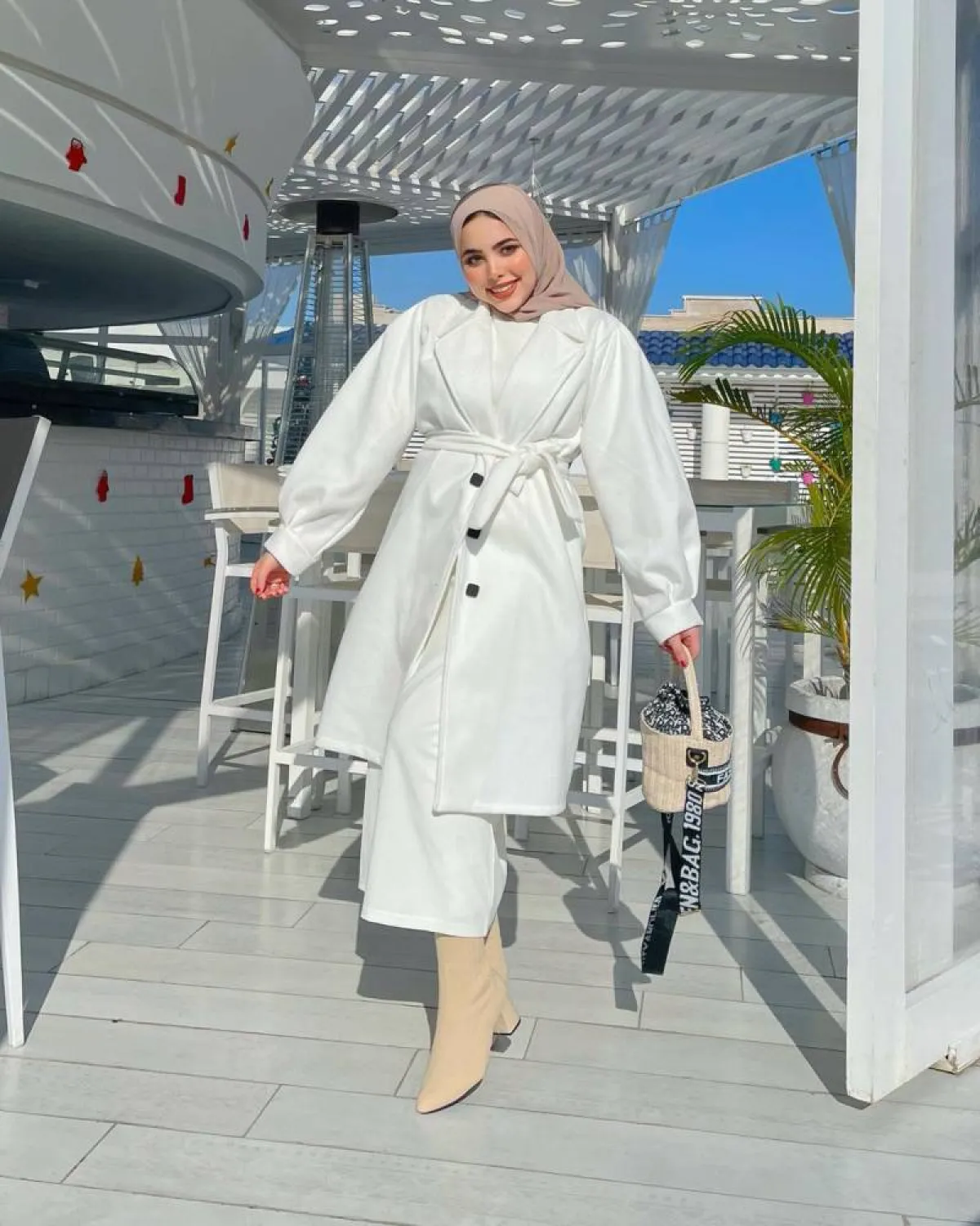 مي محمد بمعطف أبيض أوفر سايز وفستان أبيض وجزمة بوت أصفر باستيل