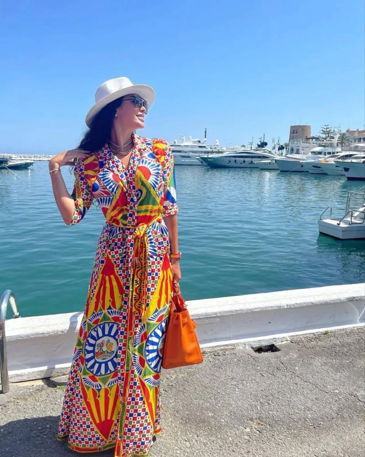 ياسمين صبري بفستان مطبع بالرسمات الشرقية الملونة مع قبعة بيضاء وحقيبة يد برتقالية اللون