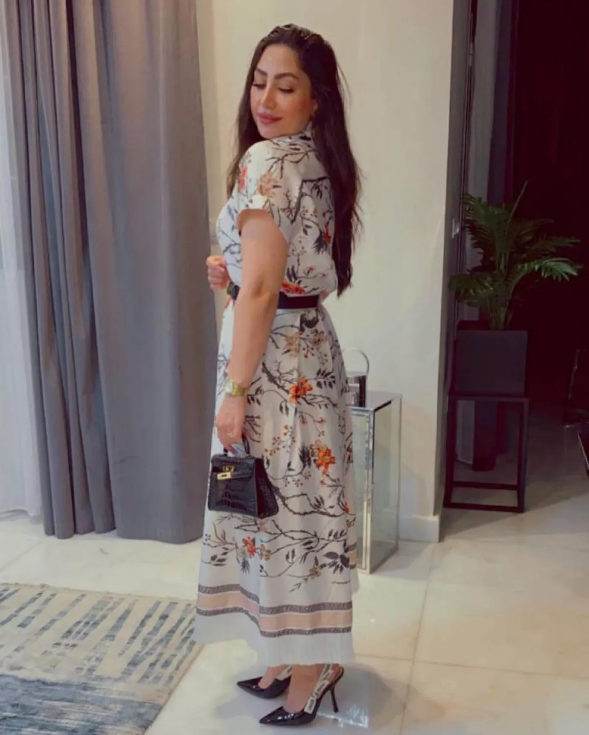 بوسي بفستان أبيض مطبع بالورود السوداء والبرتقالية مع حقيبة كلاتش سوداء