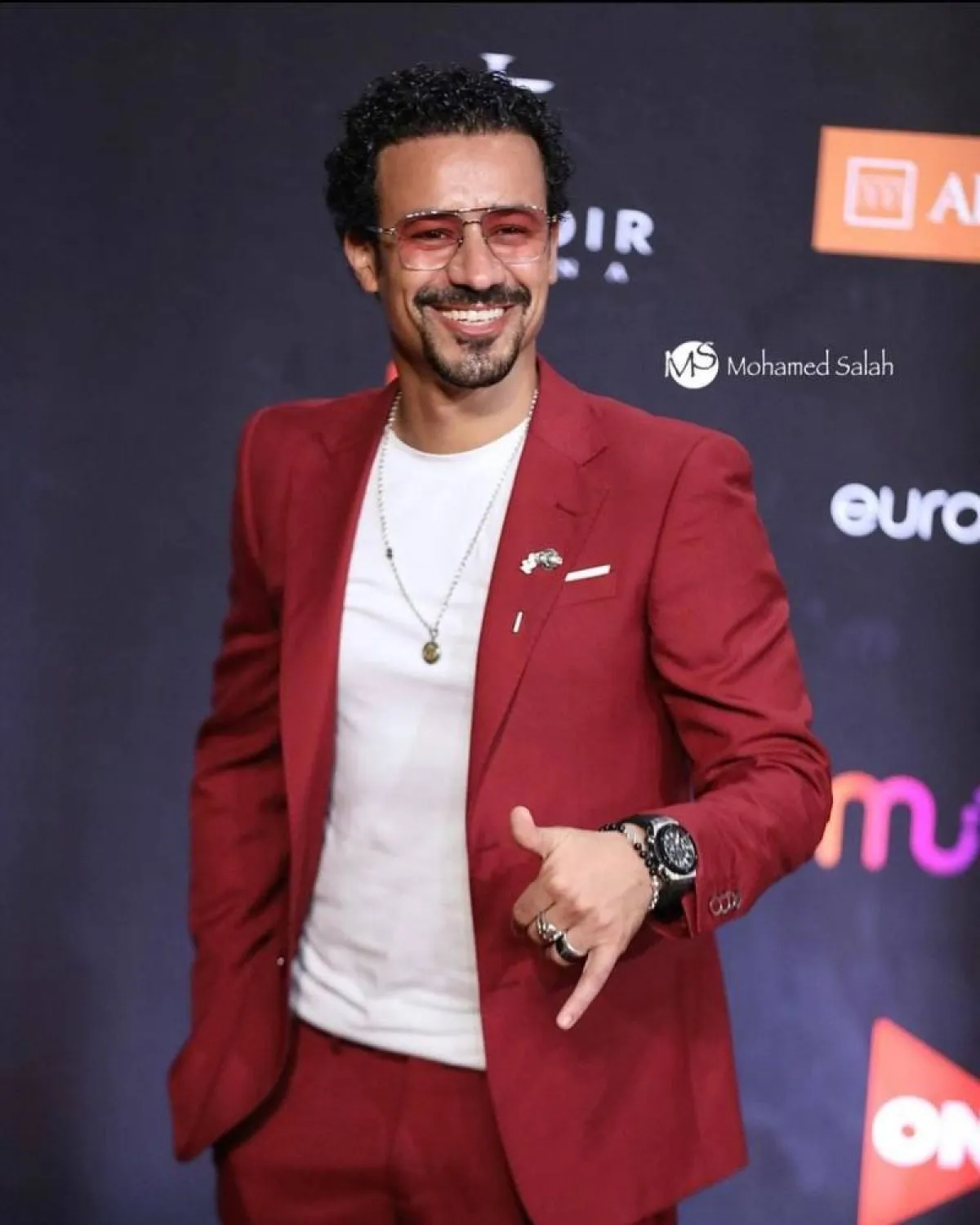 أحمد داود ببليزر باللون أحمر الداكن مع بنطلون أحمر وتيشرت أبيض