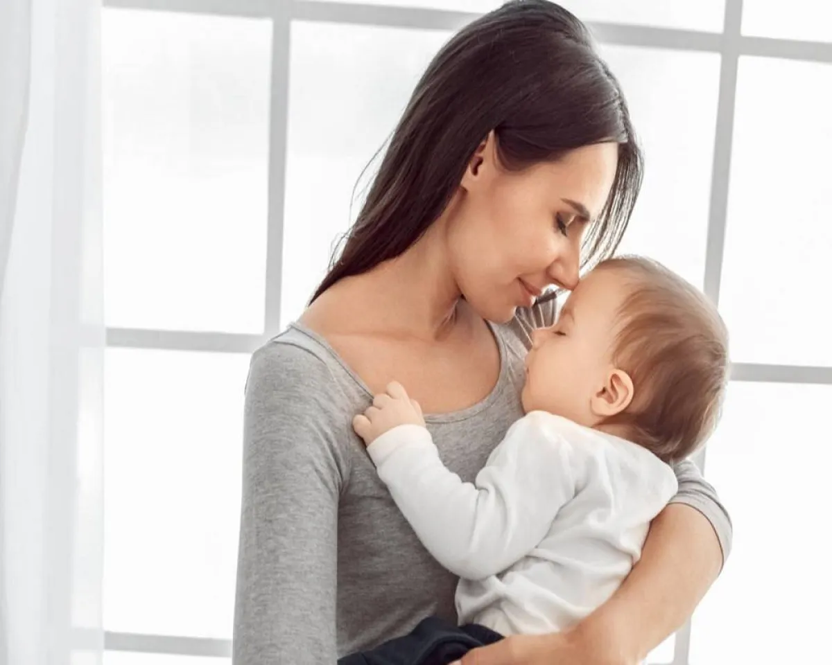 صورة لأم تحمل طفلها لتشعره بحنانها