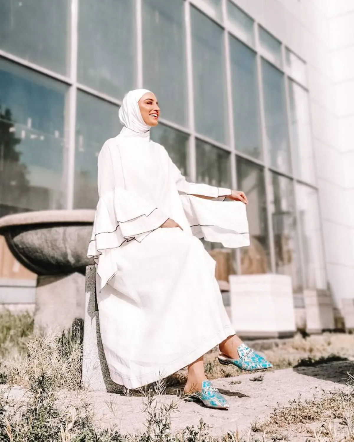 دلال الدوب بعباية بأكمام عريضة باللون الأبيض مطرزة بخطوط رفيعة سوداء