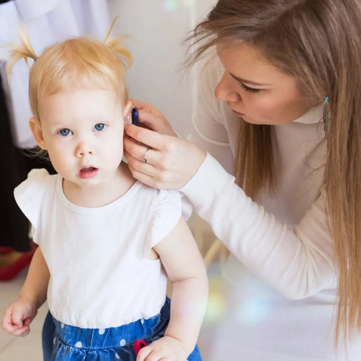 صورة لأم تركب السماعة لطفلتها