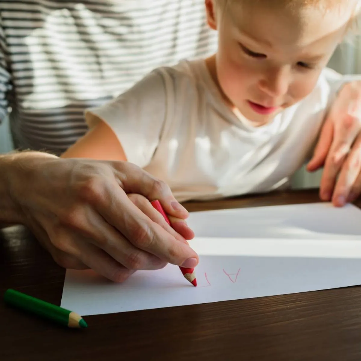 صورة لأم توجه طفلها لطريقة إمساك القلم