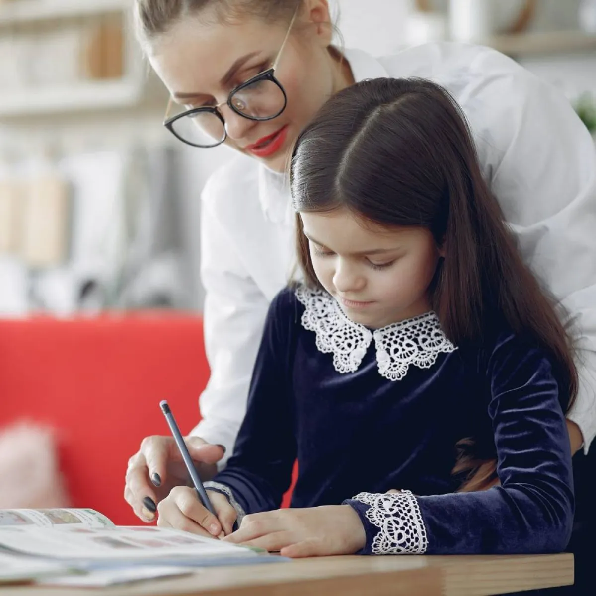 صورة لأم تعلم طفلتها الكتابة