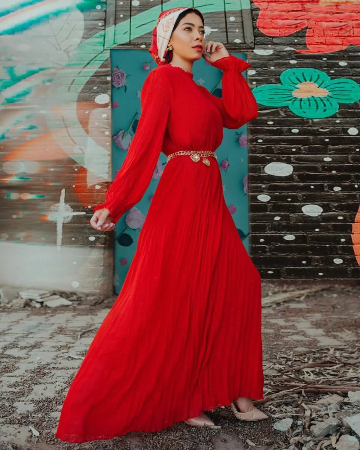 منة السني بفستان أحمر بليسيه وإيشارب باللون الأحمر والبيج