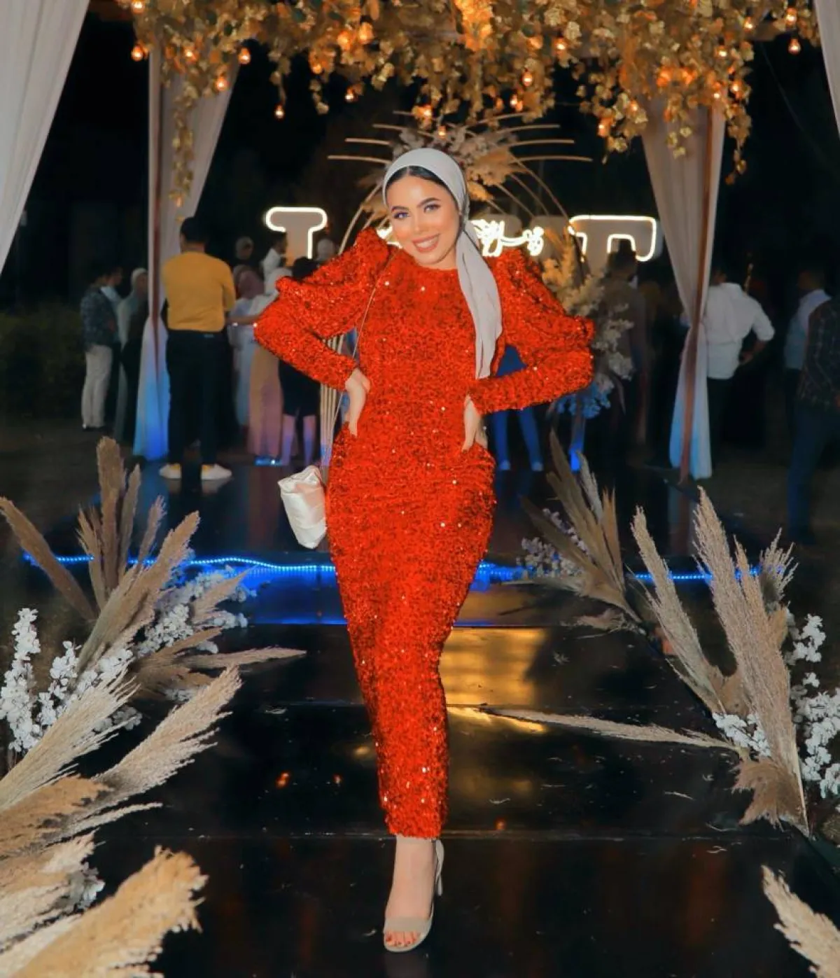 مي محمد بفستان أحمر ماكسي وإيشارب باللون الرمادي وحقيبة كتف 