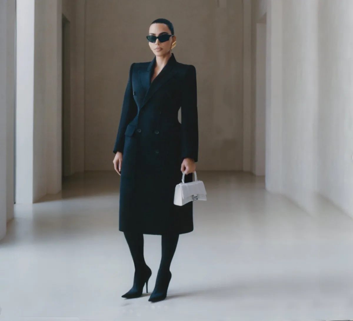 كيم كاردشيان ترتدي معطفاً أسود وتحمل حقيبة بيضاء من بالنسياغا