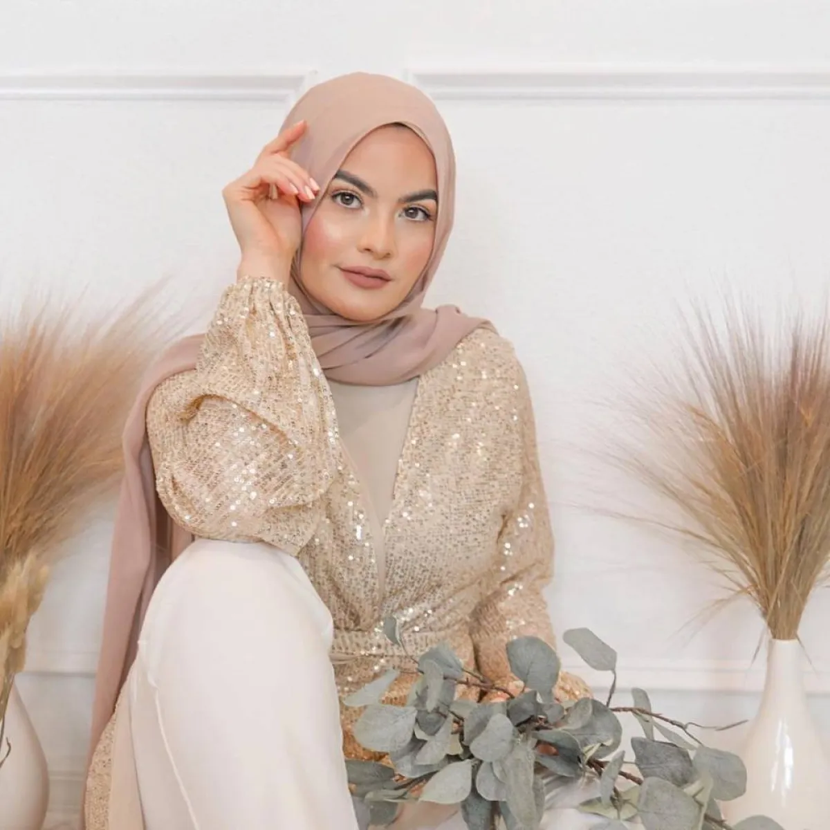 أمية زين بتوب باللون الذهبي وبنطلون باللون الأبيض 