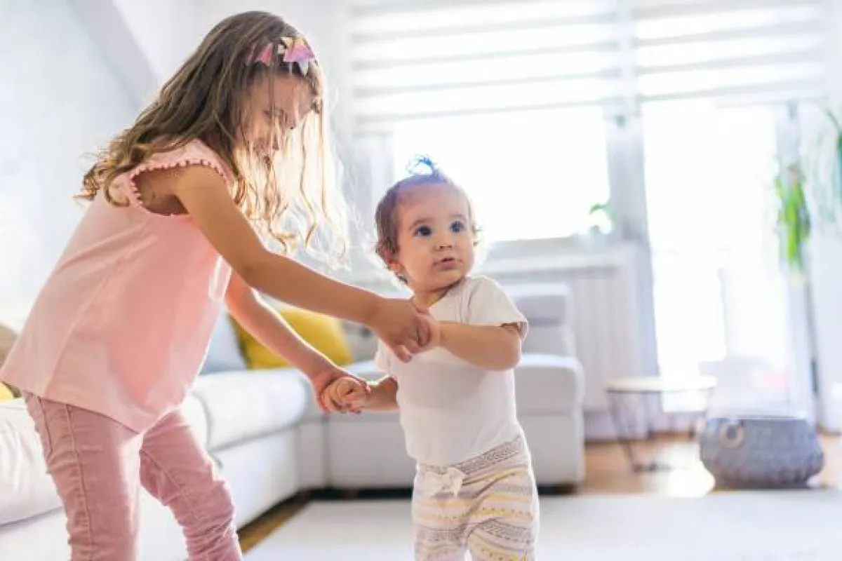صورة لطفلة تدرب شقيقها على المشي