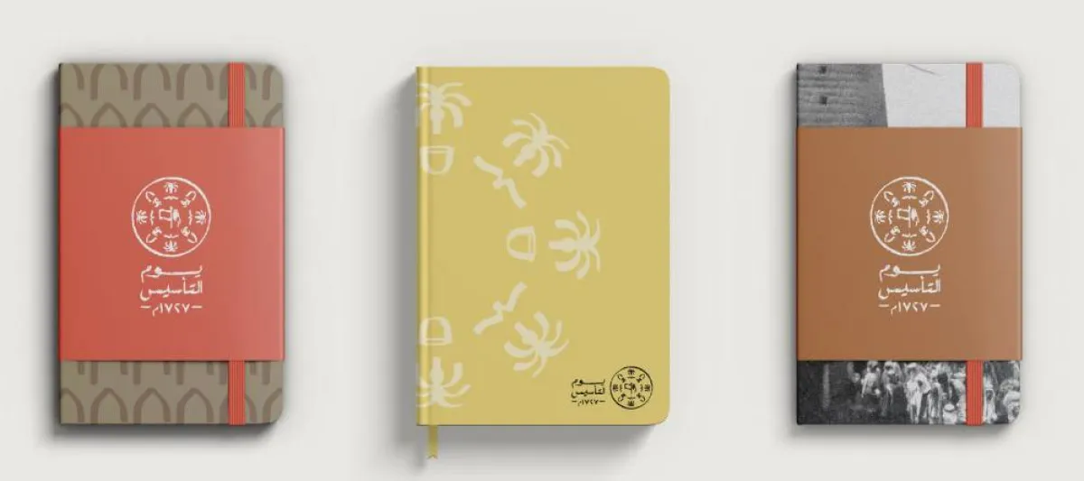 مفكّرات محمّلة أغلفتها بشعار يوم التأسيس، ورموزه