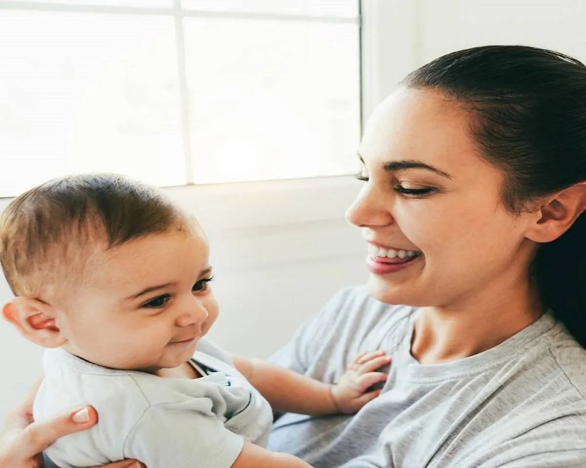 صورة لأم تتحدث مع طفلها الصغير وطفلها يبتسم